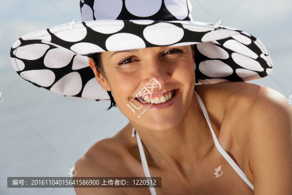 迷人的女人在海灘上戴著時(shí)髦的帽子
