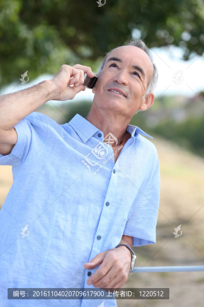 帶移動(dòng)電話的中年男子戶外