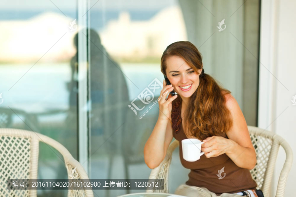 快樂的女孩講手機，在陽臺上喝咖啡