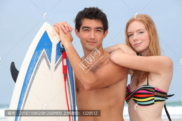 年輕的夫婦在海灘上的沖浪板