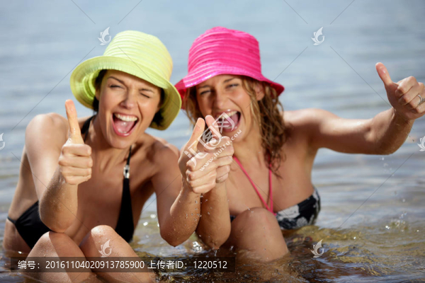 兩個(gè)女朋友在沙灘上豎起大拇指