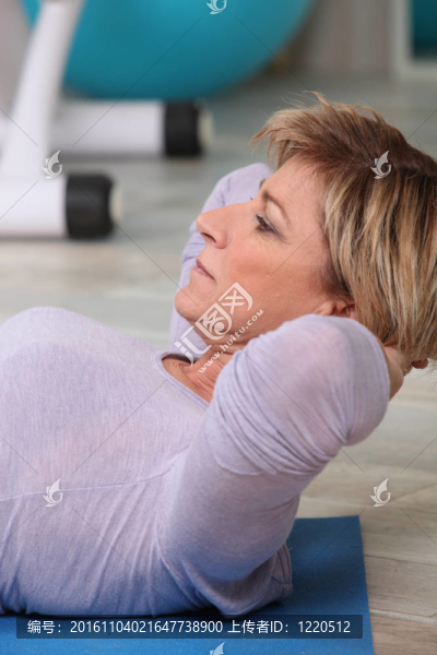 在體操墊上做坐著的女人