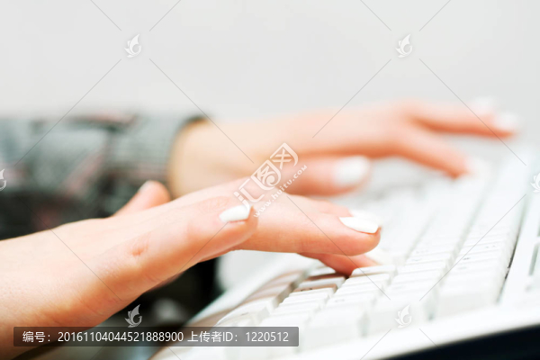 電腦鍵盤上打字的女性手。
