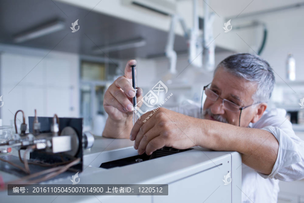 男性資深研究員開(kāi)展科學(xué)研究，在實(shí)驗(yàn)室用氣相色譜儀（淺景深；顏色色調(diào)的圖像）