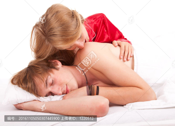 幸福的情侶在床上；女孩親吻熟睡的男朋友