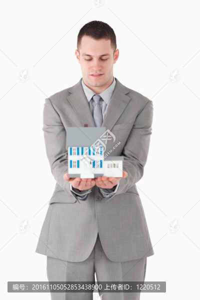 一個商人在看一個微型房子的肖像