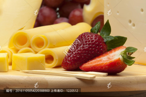 一組不同的奶酪；一塊木板上的草莓和葡萄