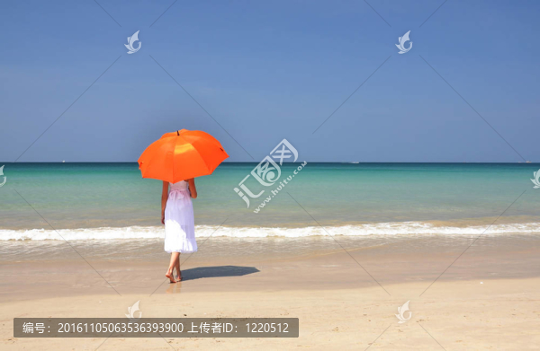 沙灘上帶著橙色雨傘的女孩