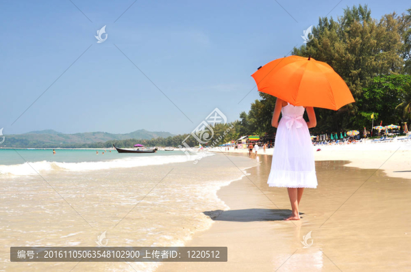 沙灘上帶著橙色雨傘的女孩