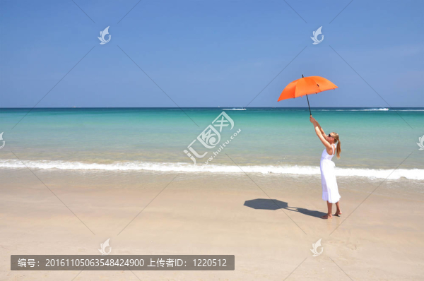 沙灘上帶著橙色雨傘的女孩
