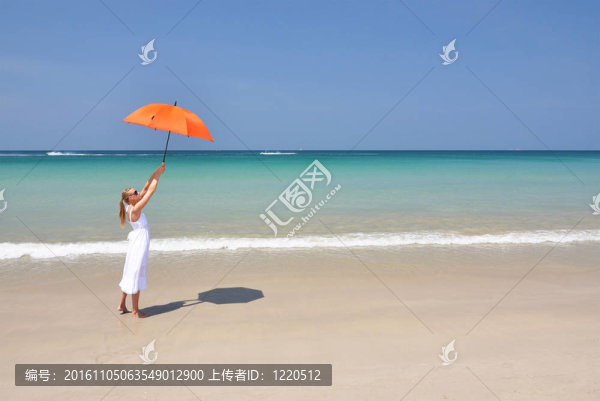 沙灘上帶著橙色雨傘的女孩