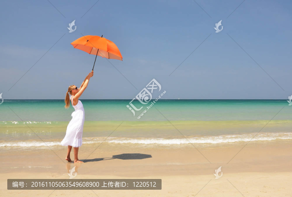 沙灘上帶著橙色雨傘的女孩