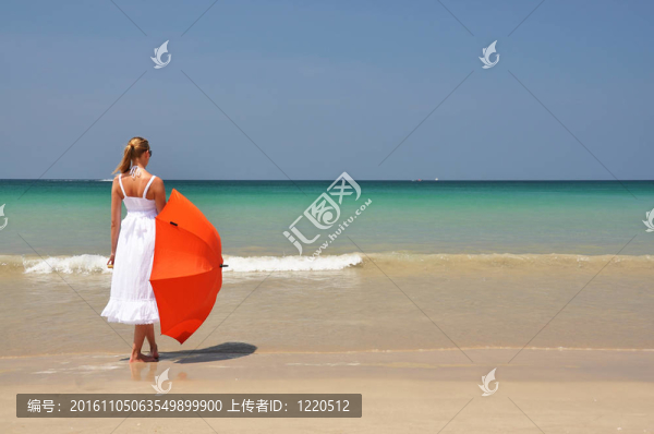 沙灘上帶著橙色雨傘的女孩