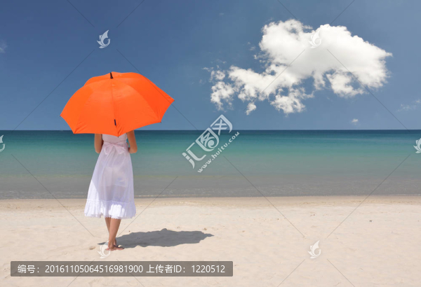 沙灘上帶著橙色雨傘的女孩