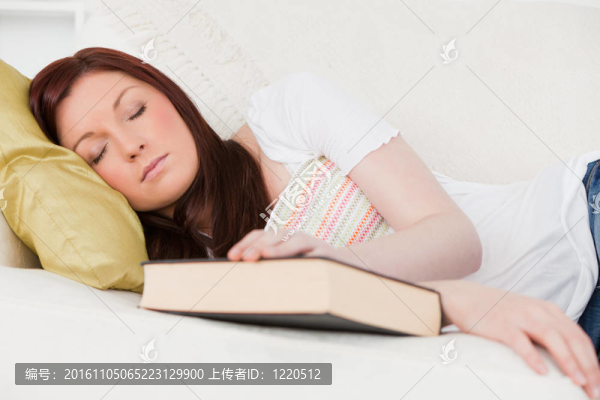 漂亮的紅發(fā)女孩在客廳的沙發(fā)上學(xué)習(xí)休息