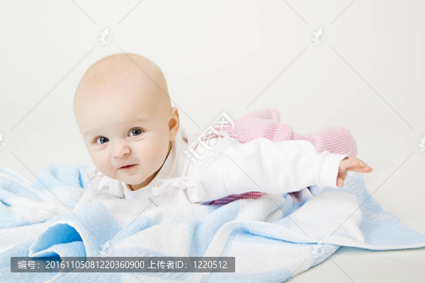 可愛的藍(lán)眼睛嬰兒在地板上的藍(lán)毛巾