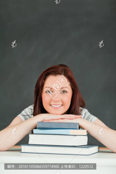 微笑的年輕學(xué)生下巴上的書(shū)