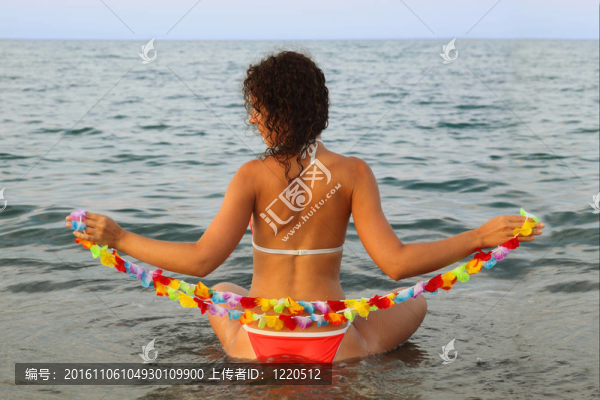 漂亮的年輕女人穿著泳衣抱著海水中花座夏威夷花環(huán)