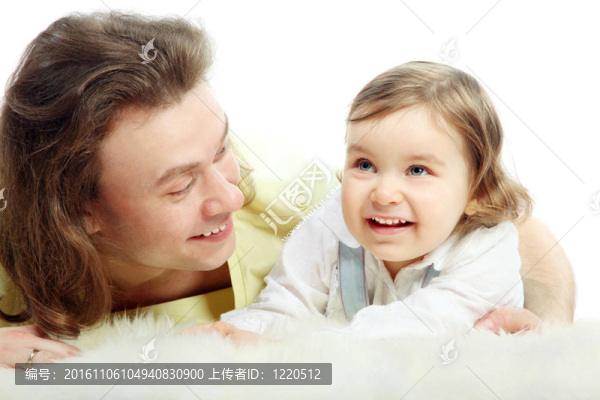 父親抱著小女兒躺在白地毯上.