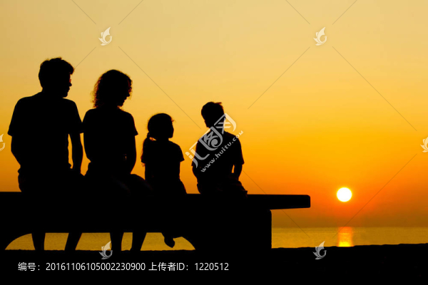 父親帶著母親和兩個孩子坐在沙灘上的長椅上，晚上和交談