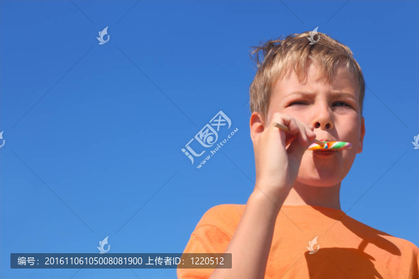 橙色襯衫吃五彩棒棒糖的小男孩；藍色的天空