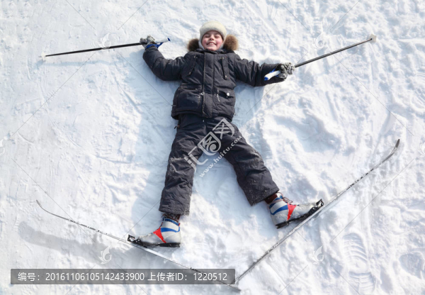 小男孩躺在越野滑雪板和桿的拉伸
