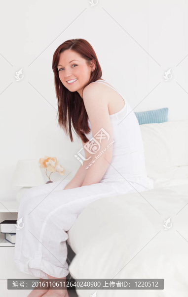 漂亮的紅發(fā)女性在坐在床上擺姿勢