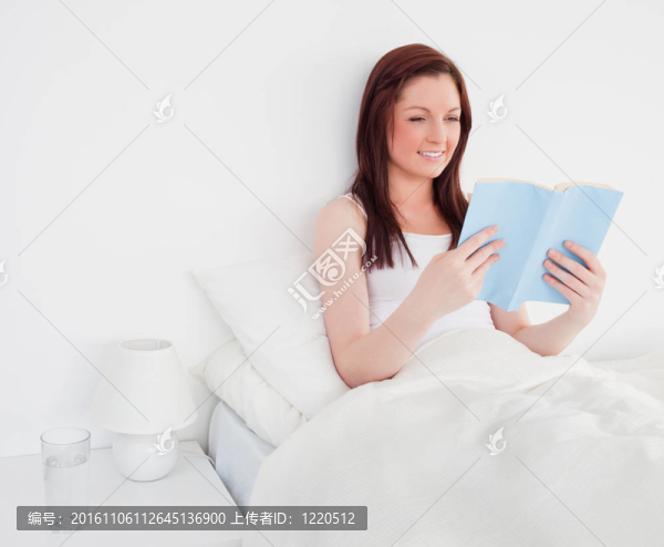 漂亮的紅發(fā)女人坐在床上看書