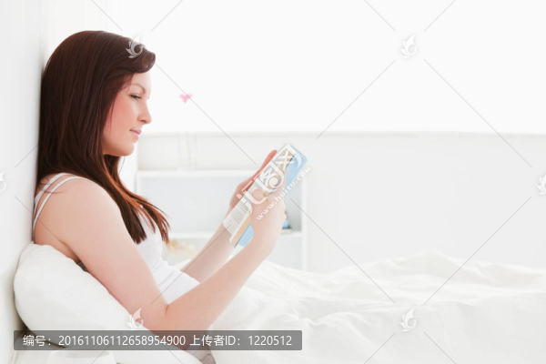 漂亮的紅發(fā)女坐在床上看書