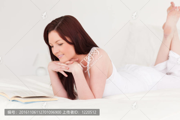 美麗的紅發(fā)女人躺在床上看書