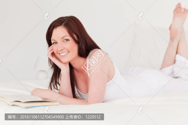 漂亮的紅發(fā)女人躺在床上看書