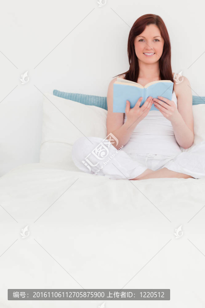 迷人的紅發(fā)女人坐在床上看書(shū)
