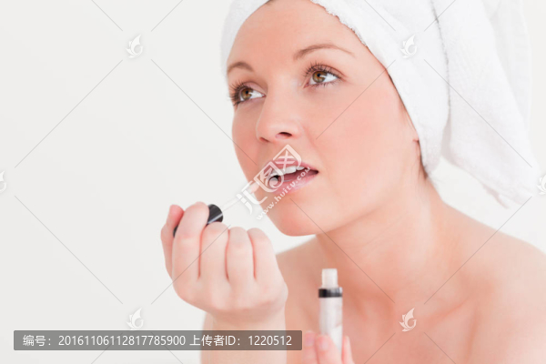 漂亮的年輕女子穿著毛巾用唇彩