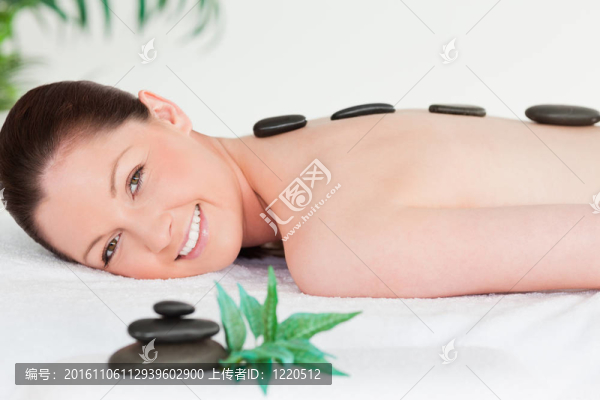 帶著按摩石的微笑年輕女子