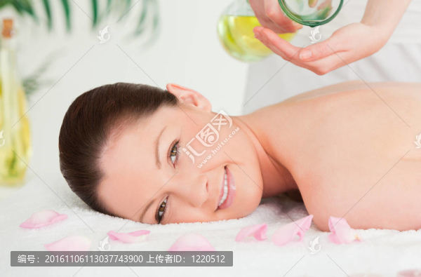 美麗的女人得到按摩油在她的背部在溫泉