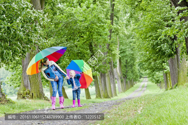 母親和女兒在春天的小巷里帶著雨傘