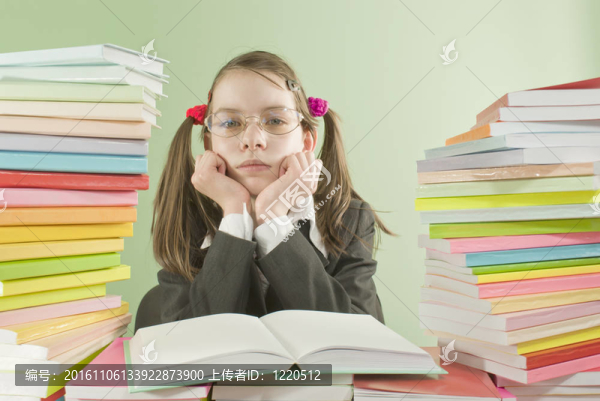 無聊的學校女孩坐在桌旁，手里拿著一摞書