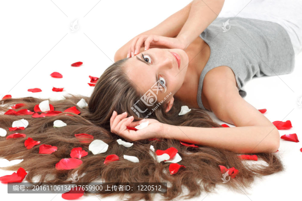 年輕漂亮的黑發(fā)女人散亂的長頭發(fā)和白色玫瑰的花瓣上