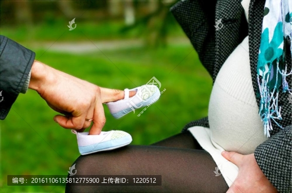 可愛的男人在他懷孕的妻子玩嬰兒鞋