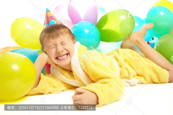 年輕的穿著微笑的小男孩慶祝他的生日，五顏六色的氣球被白色的