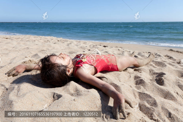 沙灘上覆蓋著沙灘的小女孩