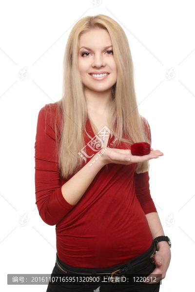 幸福的金發(fā)碧眼的年輕女子微笑著在紅色的衣服舉行一個(gè)紅色的盒子與戒指孤立的白色