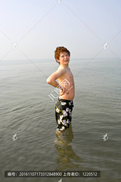 可愛的男孩站在威尼斯的海灘上的水；在意大利。