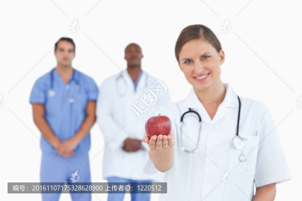 微笑的醫(yī)生提供蘋果與同事在她身后
