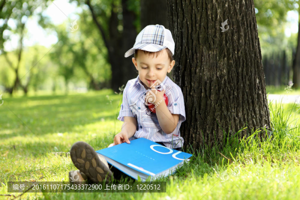 一個(gè)男孩在公園里拿著一本書(shū)的肖像