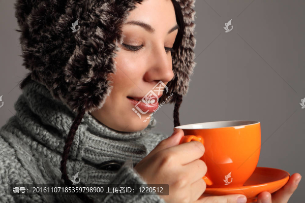 年輕女子在溫暖的冬天帽子喝熱茶