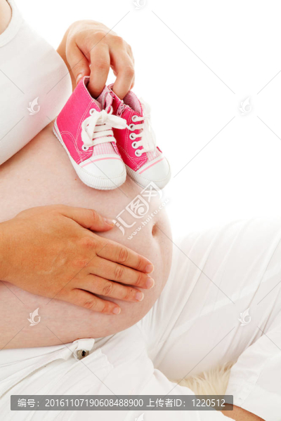 女人抱著小粉紅色的鞋子超過懷孕的肚子