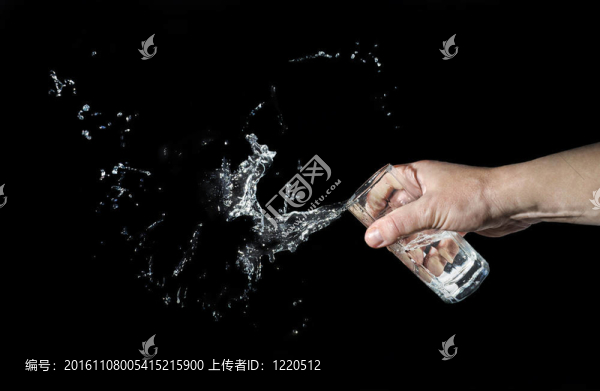 男人在黑色背景上從玻璃杯里扔水