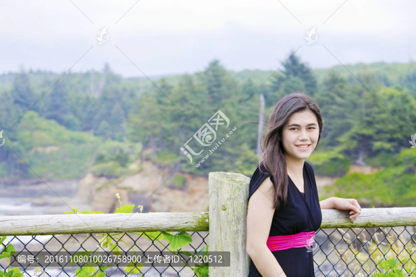 微笑的少女穿著黑色禮服站在海邊