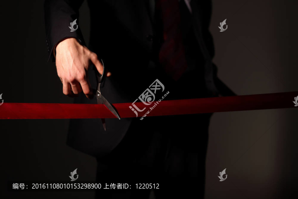 用剪刀切一個紅絲帶的商人